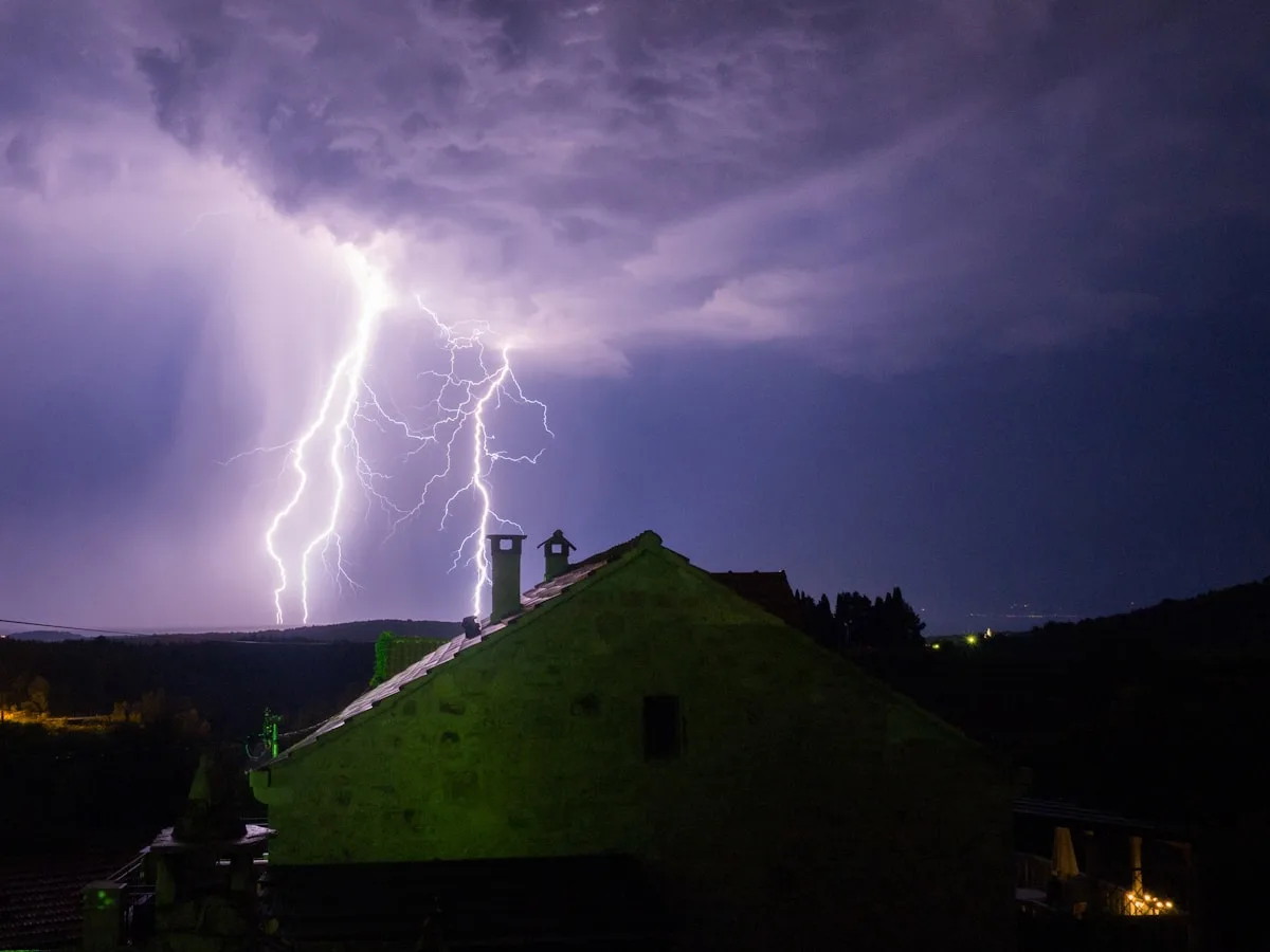 A lightning bolt striking over a house at night